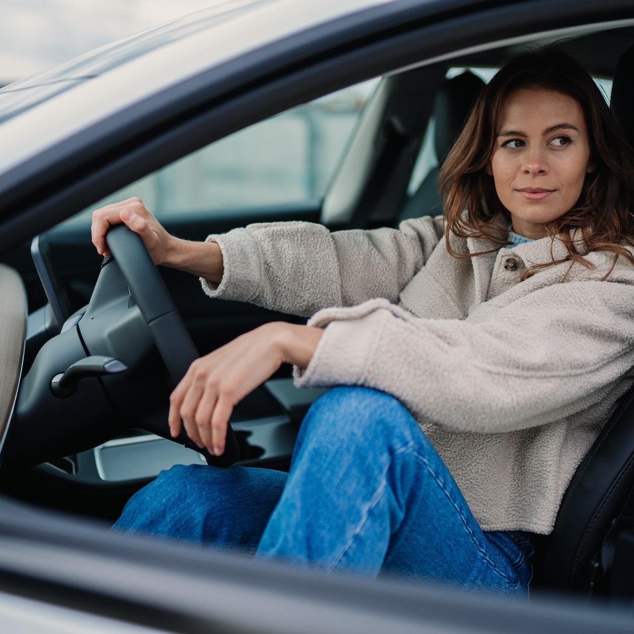 woman in gray sweater and blue denim jeans sitting on car seat